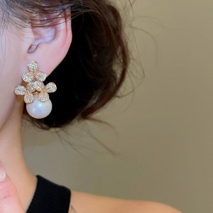 Detail of three-flower stud earrings with micro-set zircons and a large white pearl drop