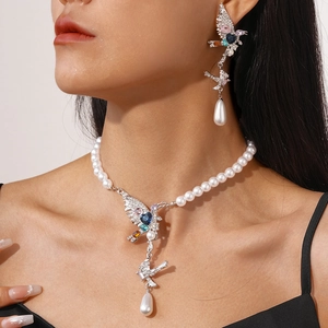 Close-up of bird-shaped pearl necklace and earrings with multi-colored gemstones