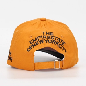 Dettaglio del cinturino in metallo e ricamo NYC sul cappellino da baseball in cotone arancio