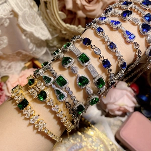 Vintage gold and silver bracelets with green and blue crystals on a model's wrist