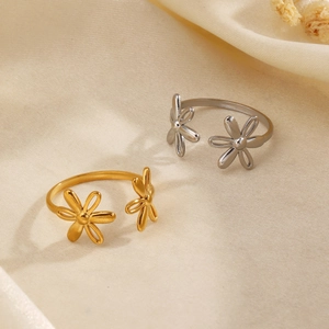 Minimalist stainless steel flower rings in gold and silver on a beige silk background