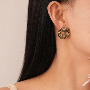 Close-up of vintage French gold earrings with champagne stone and beaded edge details