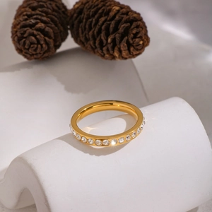 Polished gold stainless steel ring with micro-pave round zircons on a white pedestal