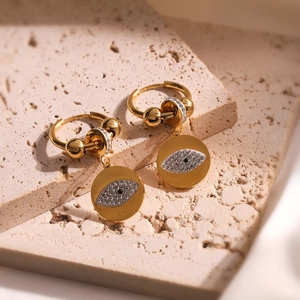 Gold-plated evil eye hoop earrings with sparkling cubic zirconia on a stone surface