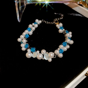 Detail of blue and white pearl bracelet with cat eye stones on black velvet background