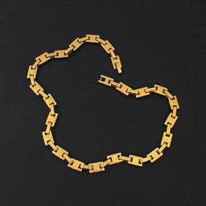 Close-up of gold-plated H-link chunky chain necklace on textured black background