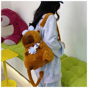 Back view of a plush Capybara backpack with a white rabbit pendant worn by a model