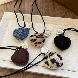 Detail of heart pendants with various textures like denim and leopard print on black cords