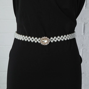 Detailed view of multi-layer pearl waist belt with a sparkling rhinestone buckle on a dress