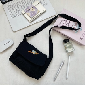 Close-up of black canvas crossbody bag featuring a colorful planet embroidery detail