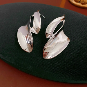 Detail shot of silver abstract twisted leaf earrings on a black velvet display stand