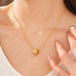 Close-up of 18k gold plated cylinder necklace with cubic zirconia worn by model