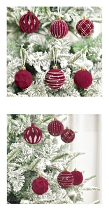 Detail of red flocked Christmas ornaments with hollow patterns on white snowy tree branches
