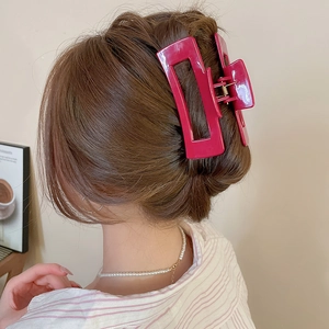 Macro shot of a hot pink square hair claw clip securing a deep brown bun hairstyle