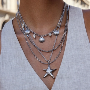 Close-up of layered silver starfish necklace with seashell charms and Cuban link chain