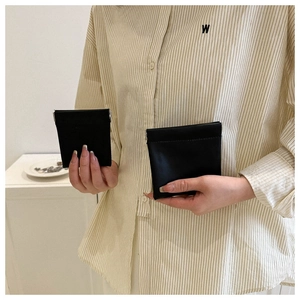 Close-up of model holding two sizes of black leather mini coin and lipstick bags