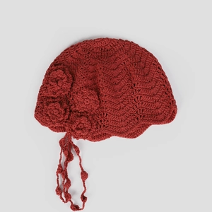 Macro shot of dark red handmade crochet beret with 3D floral details and tassels