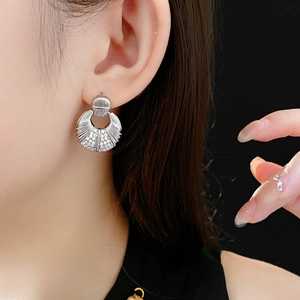 Détail de boucles d'oreilles argentées en forme d'éventail avec zirconiums sur modèle