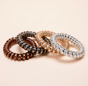 Detail of four metallic spiral hair ties in silver, rose gold, grey, and copper colors