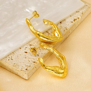 Détail de boucles d'oreilles plaquées or 18 carats avec texture de lave sur pierre
