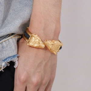 Close-up of men's wolf head steel bracelet with braided wire on wrist with denim jacket