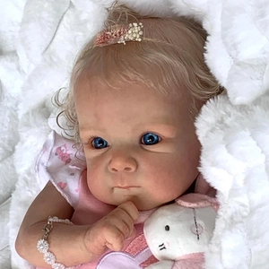 Close-up of Bettie reborn baby doll face with blue eyes and floral headband