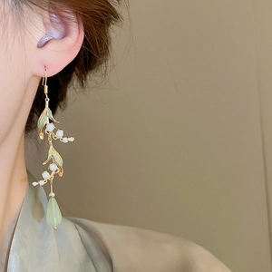 Detail of Lily of the Valley earrings with green resin drops on a female model