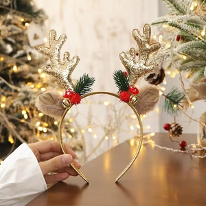 Detail of glitter reindeer antlers headband with gold bells and festive greenery