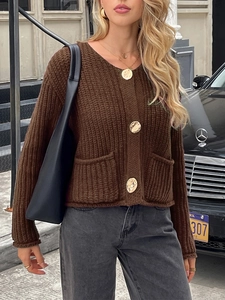 Détail d'un gilet en maille marron avec col en V, grands boutons dorés et poches frontales