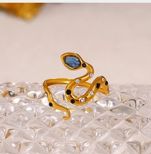 Detailed macro shot of 18K gold snake ring with a blue gemstone and crystal accents