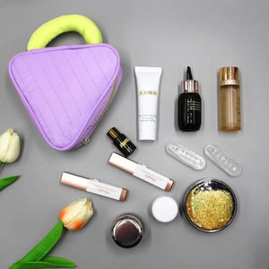 Purple quilted makeup bag with green handles displaying skincare and cosmetic products
