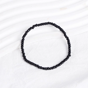 Close-up of black beaded bracelet with polished round beads on white textured background