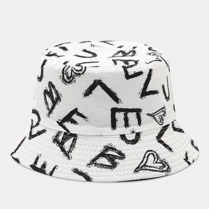 Close-up of white canvas bucket hat featuring black graffiti letters and heart patterns