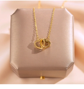 Detailed close-up of 18k gold interlocking double heart pendant with sparkling crystals