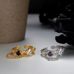 Detail of S925 silver rings with hammer texture, dangling chains and colored gemstones