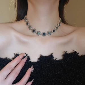 Detailed close-up of a vintage floral necklace with dark blue crystals on metal base