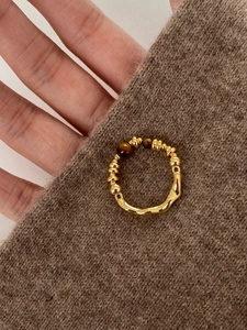 Detail of 18K gold plated tiger eye ring on brown knit sweater with retro design