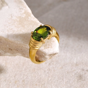 Detailed macro view of 18k gold-plated ring with oval green stone and wave patterns