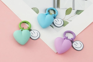 Detail of heart-shaped silicone keychains in blue green and purple with smiley face tags