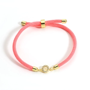 Detail of adjustable pink braided rope bracelet with gold crystal-encrusted charm