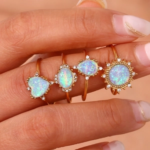 Set of four 18K gold plated adjustable rings with opal stones and crystals on female fingers