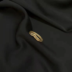 Close-up of dual V-shaped 18K gold titanium steel rings on black silk fabric