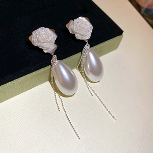 Detail of silver rose earrings with pearl teardrop and long metallic fringe tassels