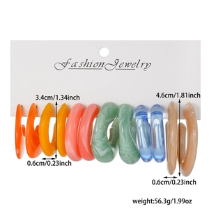 Detail view of colorful C-shaped resin hoop earrings with marble texture on display card