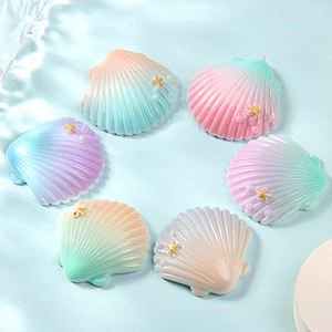 Macro view of six gradient resin shell charms with gold stars and pearl accents
