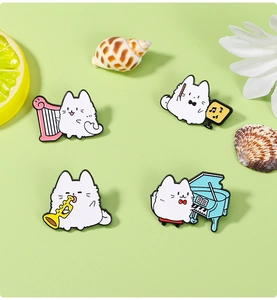 Detailed view of four cute enamel cat pins playing instruments on a green background