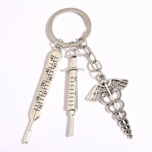 Medical keychain with silver thermometer, syringe, and Caduceus charm on white background