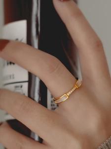 Detail of gold-plated titanium ring with white shell inlay and five sparkling zircons