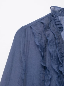 Macro-opname van delicate ruches aan de halslijn en plissédetails op een lichtblauwe blouse