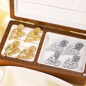 Hollow heart stud earrings in gold and silver finish with rhinestones on a silk background